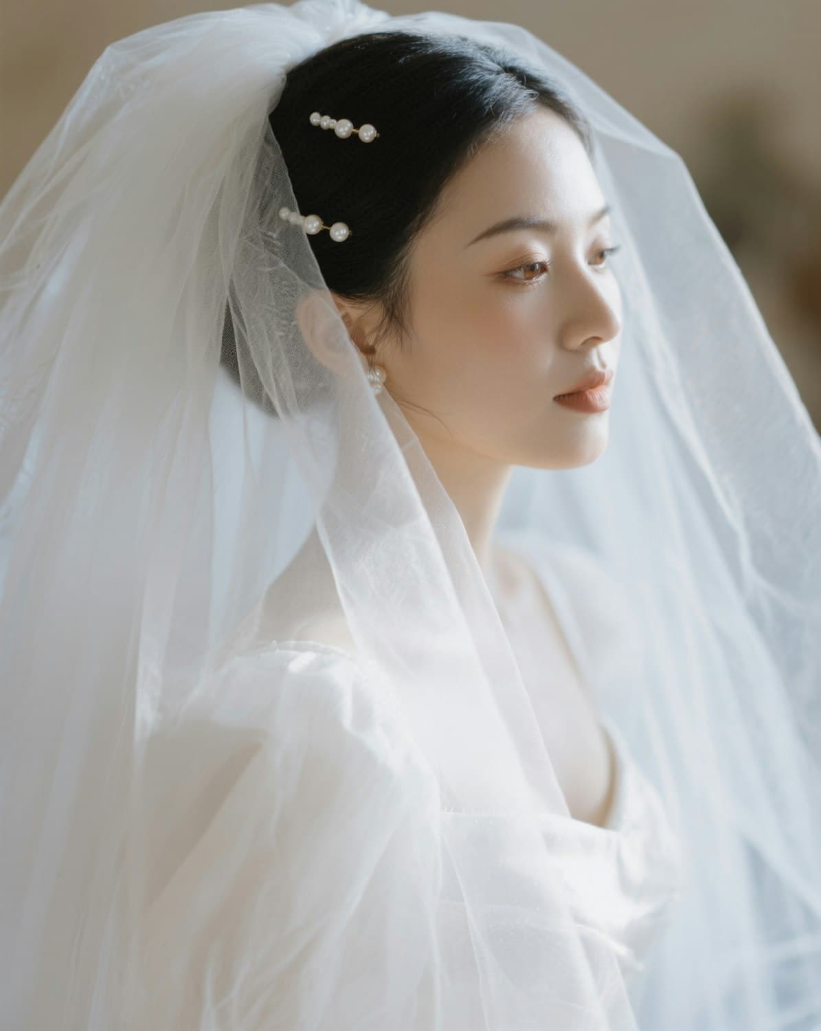 A bride in a tulle veil looking away from the camera in soft afternoon light